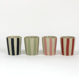 A set of four striped ceramic cups in black, green, pink and red