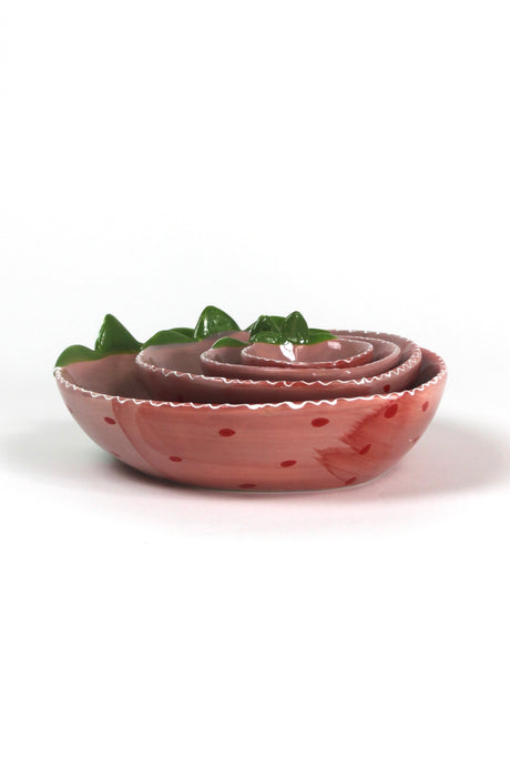 a set of four pink ceramic strawberry dishes in graduating sizes. 