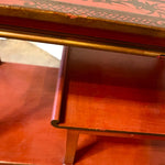 a dark wood chinoiserie side table with two tiers and on rolling casters.