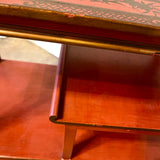 a dark wood chinoiserie side table with two tiers and on rolling casters.