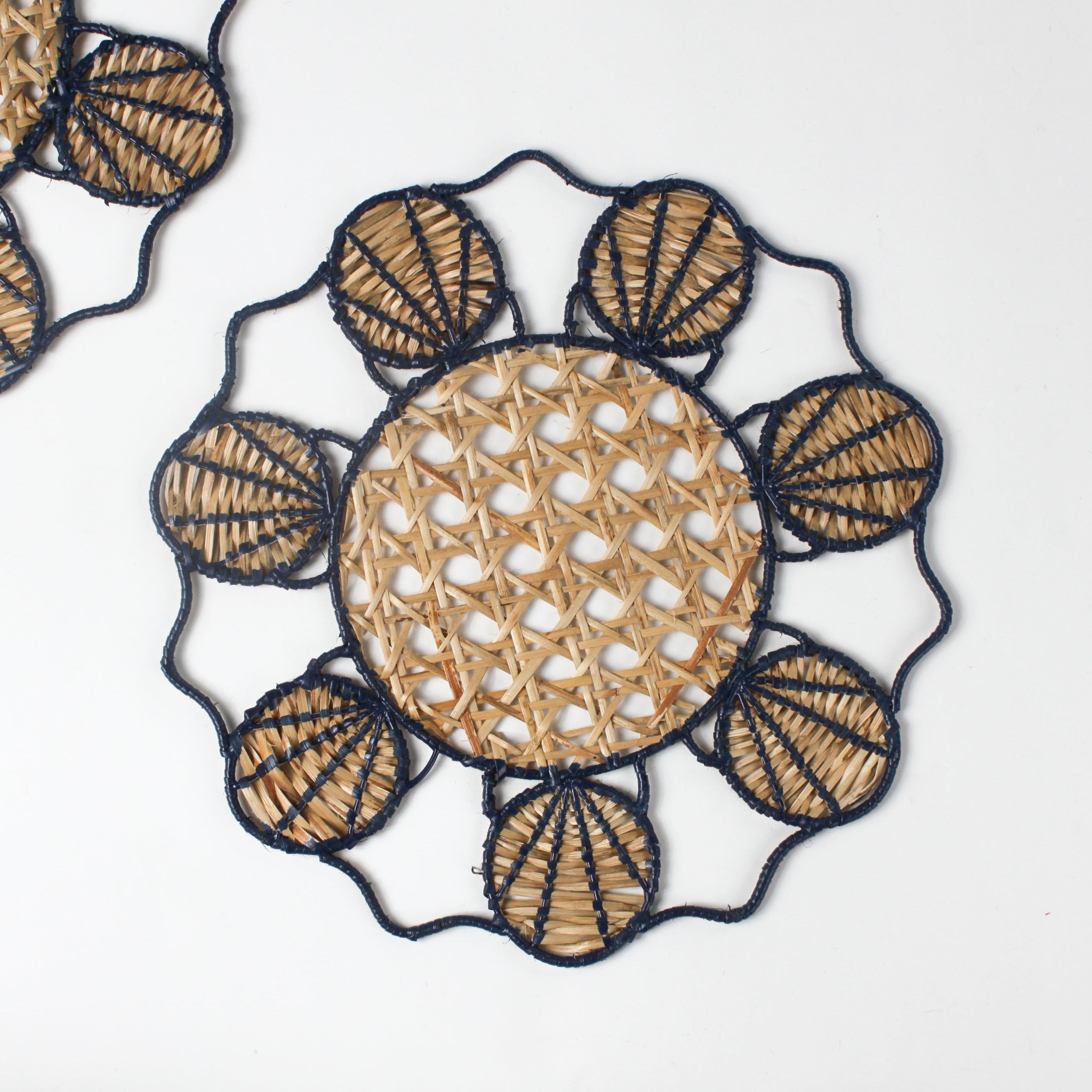 Decorative woven rattan placemat with shell patterns on a white background