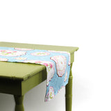 Side view of a blue decorative table runner draped over a green table.