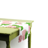 Side view of a strawberry-patterned table runner draped over a green table.