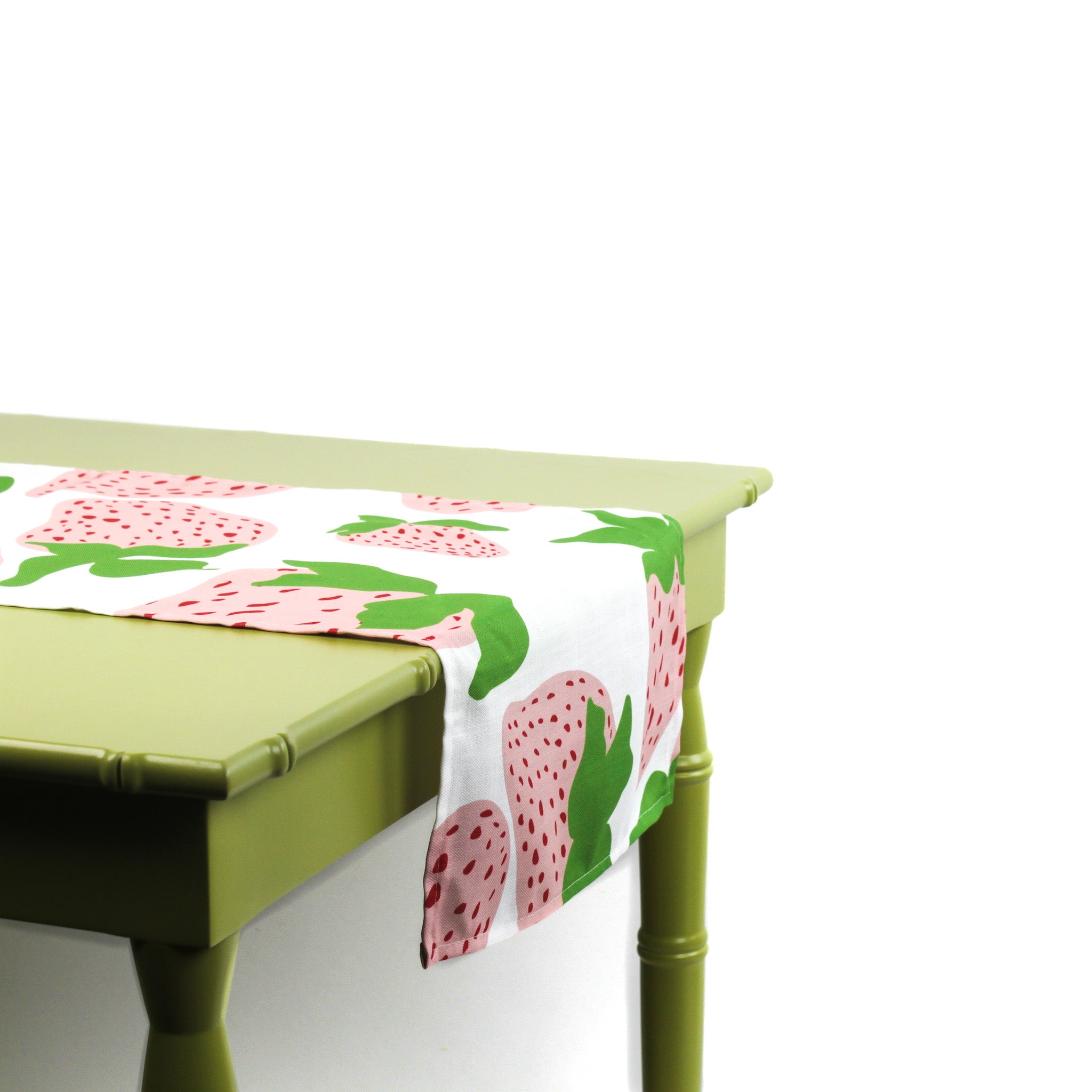 Side view of a strawberry-patterned table runner draped over a green table.