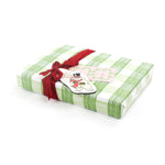 Wrapped gift in green gingham Christmas paper with red ribbon and festive tag.