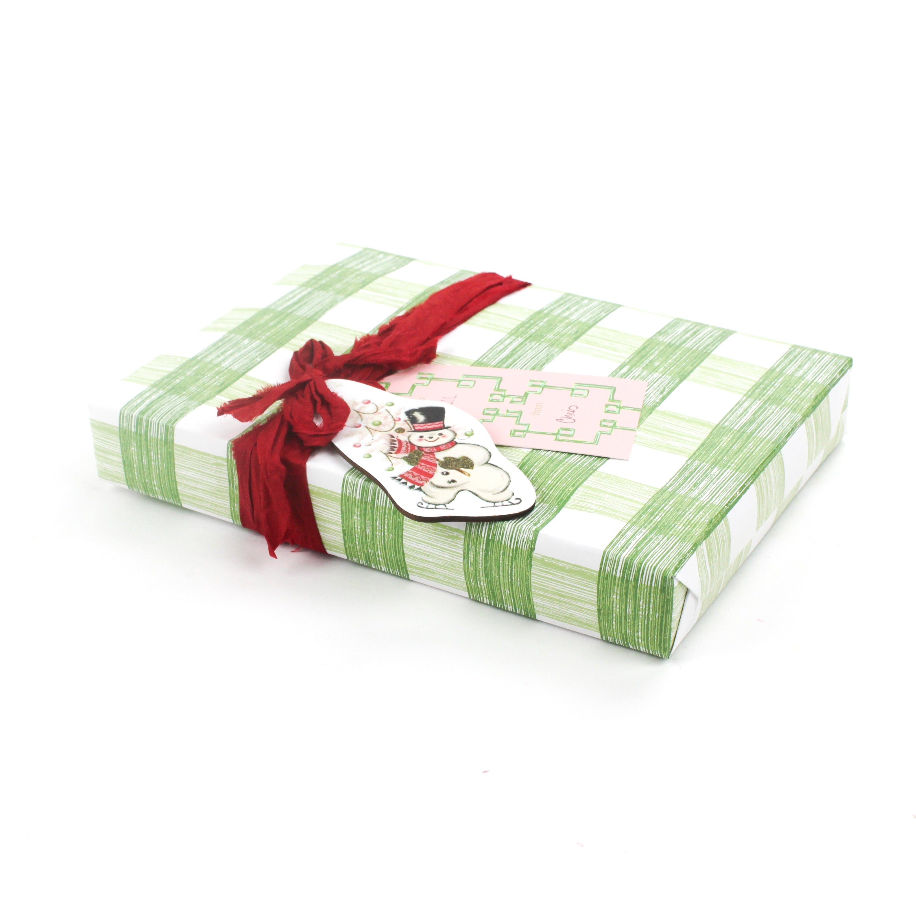 Wrapped gift in green gingham Christmas paper with red ribbon and festive tag.