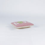 A pink pillow with the word "LOVE," where the "O" is a green tennis ball.