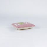 A pink pillow with the word "LOVE," where the "O" is a green tennis ball.