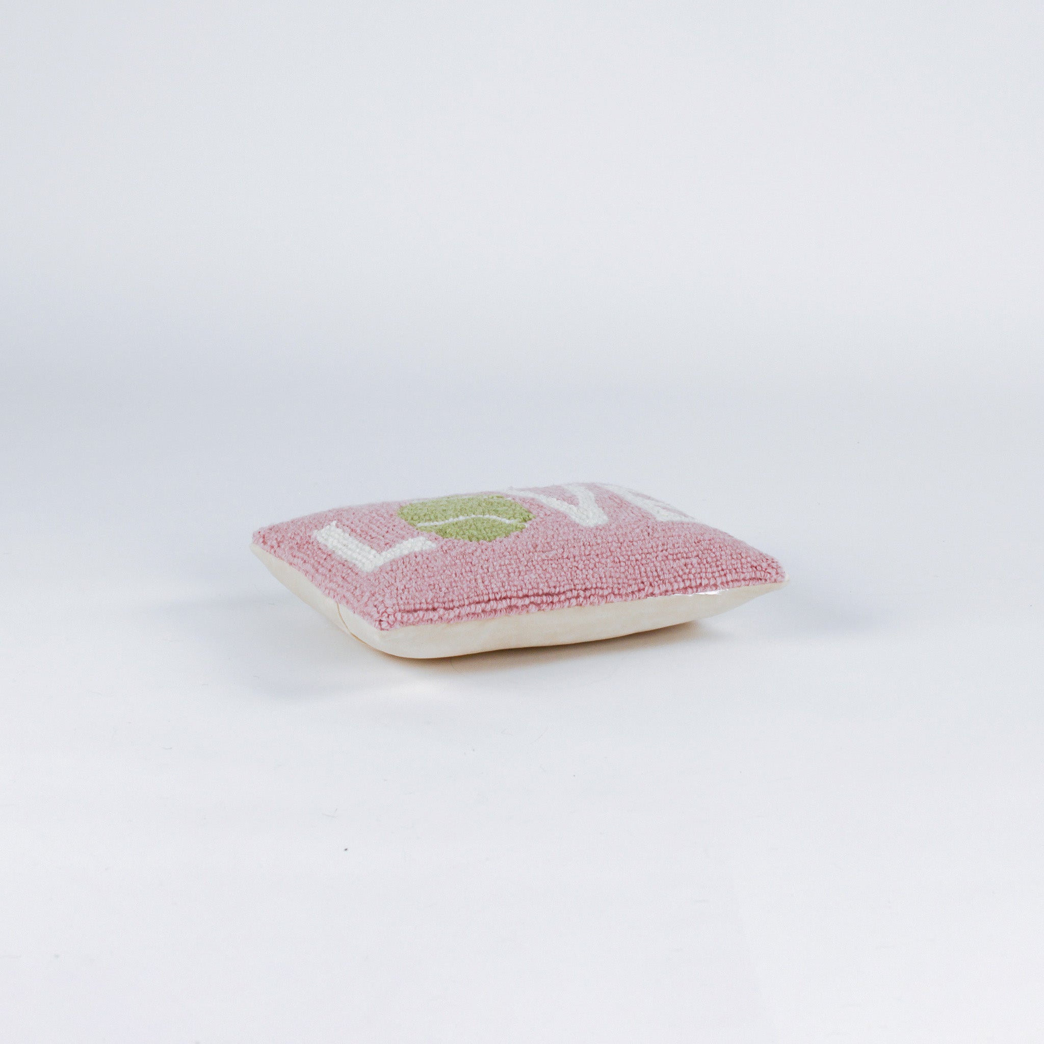 A pink pillow with the word "LOVE," where the "O" is a green tennis ball.