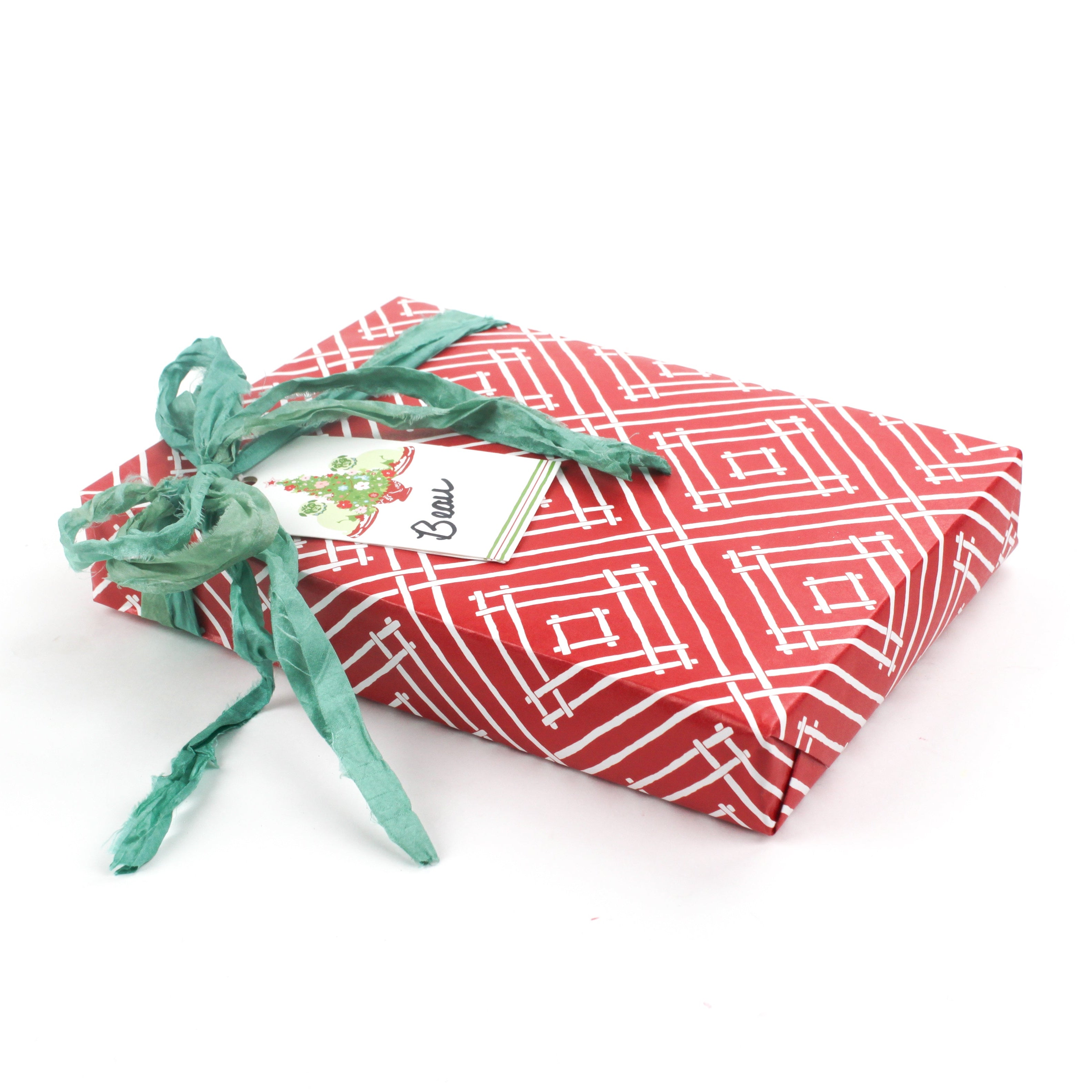Red geometric wrapping paper displayed wrapped on a flat gift with green ribbon.