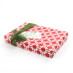 Wrapped gift in red Monserrat patterned paper with green ribbon and gift tag.
