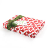 Wrapped gift in red Monserrat patterned paper with green ribbon and gift tag.