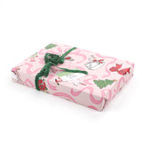 Side view of gift wrapped in pink nutcracker Christmas wrapping paper with green velvet ribbon.
