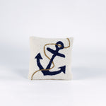 A white pillow featuring a dark blue anchor design with a tan rope wrapped around it.