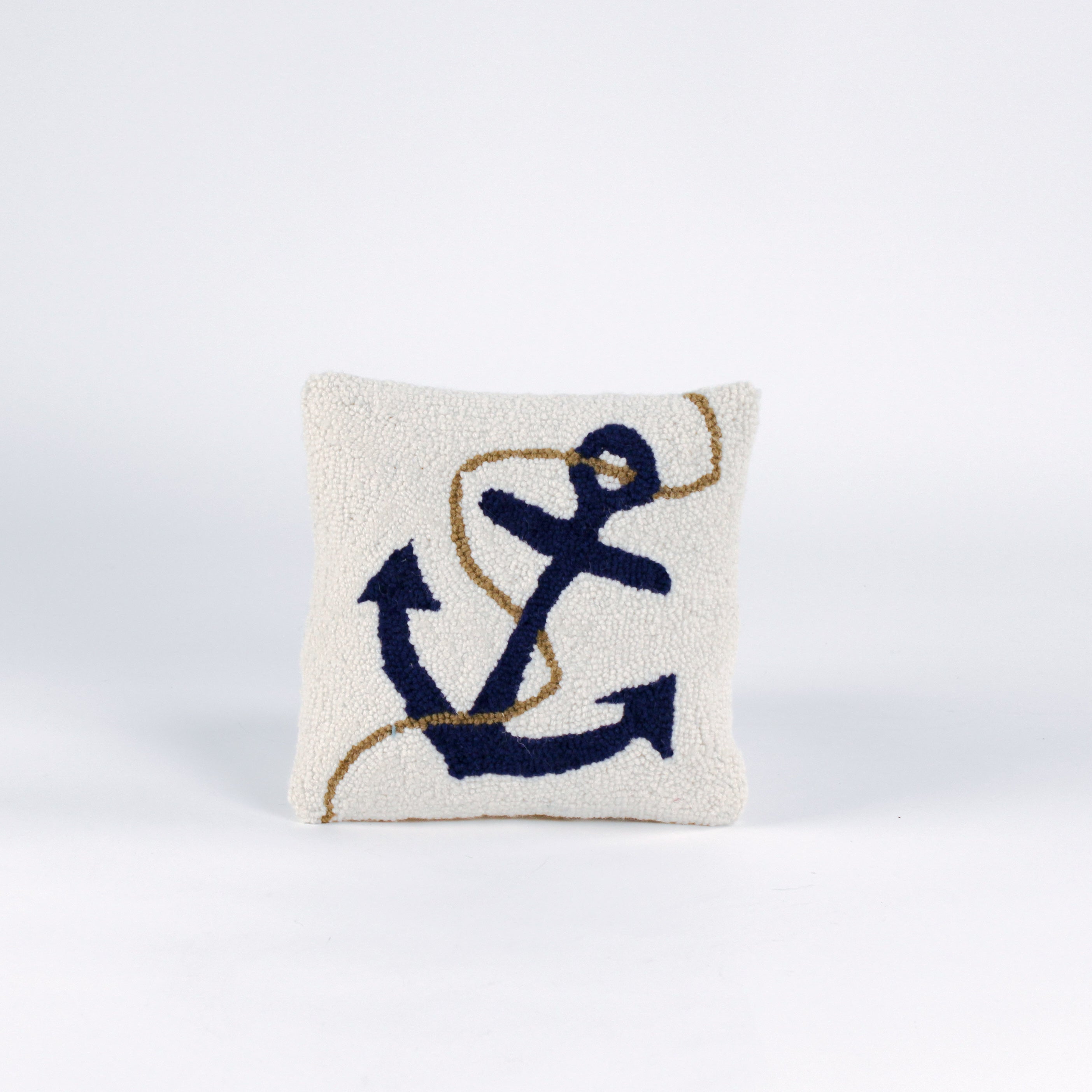 A white pillow featuring a dark blue anchor design with a tan rope wrapped around it.