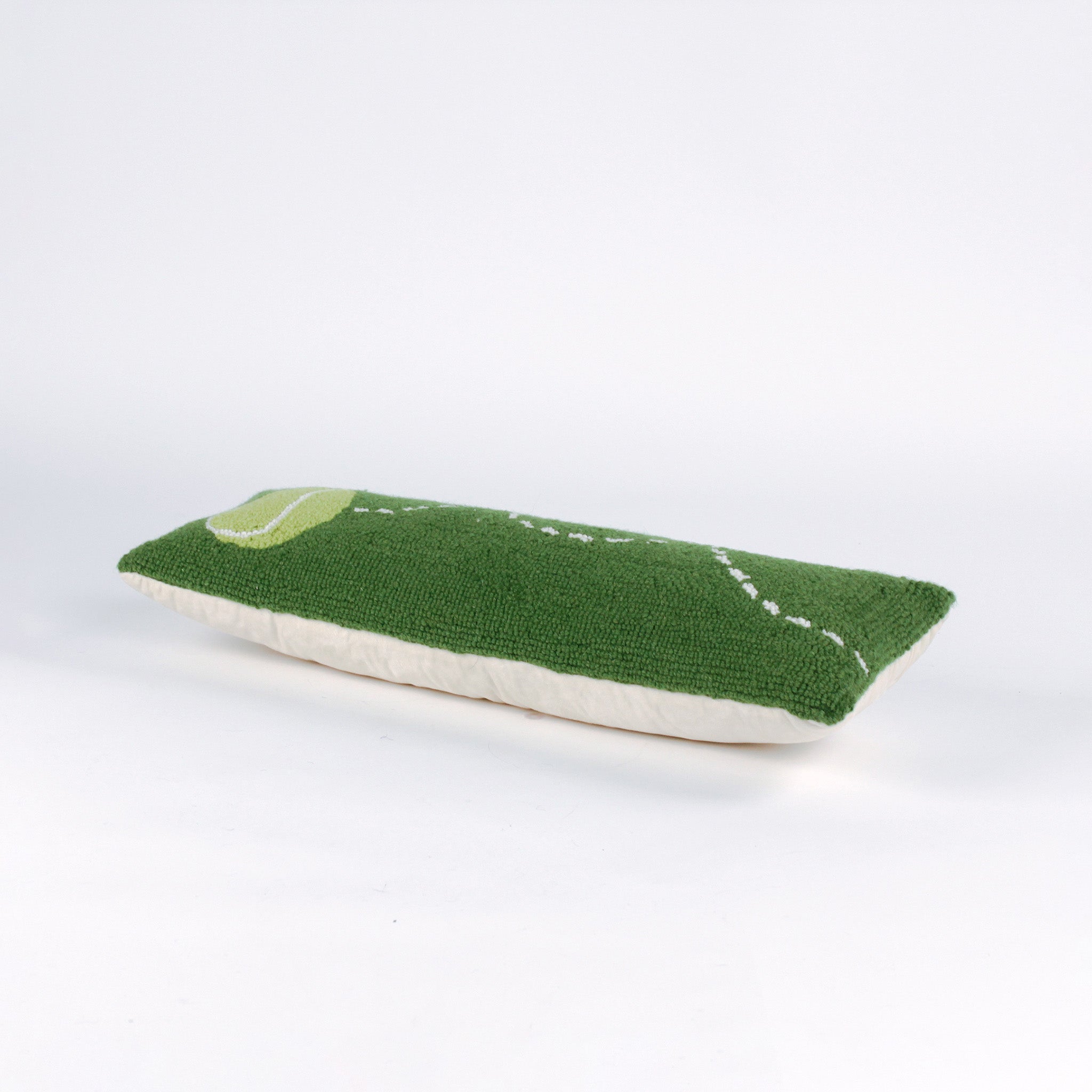 Rectangular green decorative pillow with a hooked texture, featuring a yellow tennis ball and a white dashed line illustrating its bounce pattern.