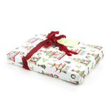 Side view of gift wrapped in pagoda Christmas print paper with red ribbon and green gift tag.