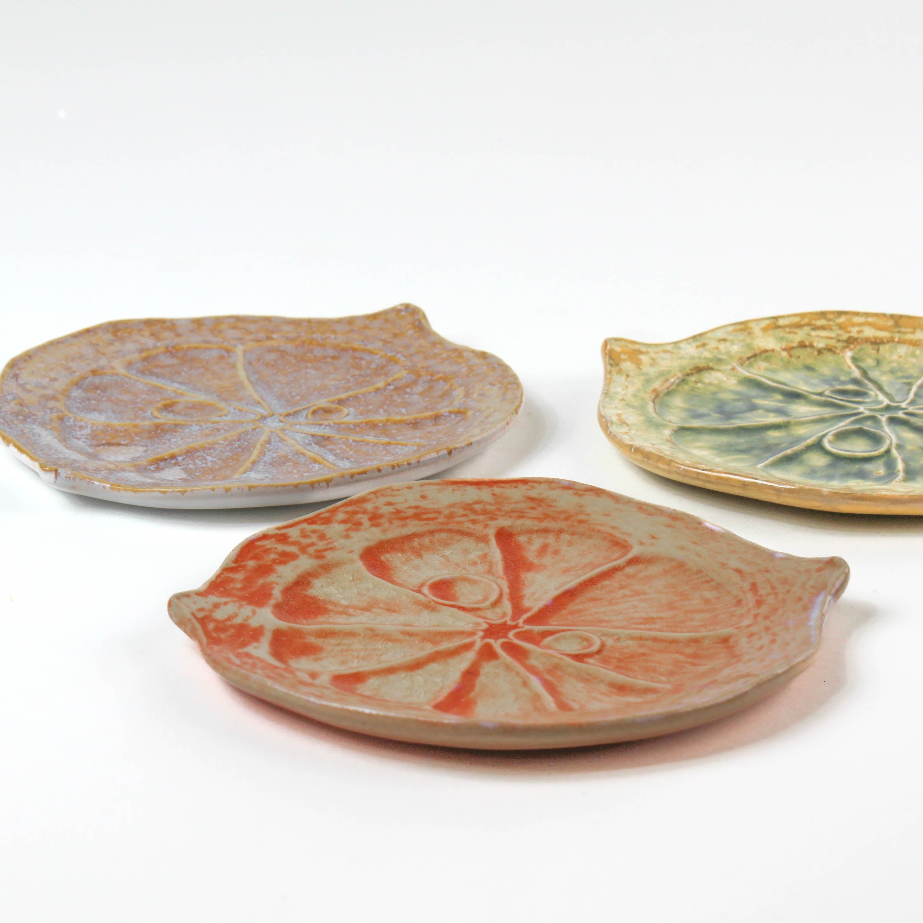 three citrus fruit shaped ceramic plates with decorative citrus patterns on a white background