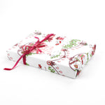 Side view of gift wrapped in holiday mouse-themed wrapping paper with pink ribbon and gift tag.