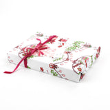 Side view of gift wrapped in holiday mouse-themed wrapping paper with pink ribbon and gift tag.