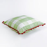 Square decorative pillow with a light green gingham plaid pattern on a white background, finished with a red scalloped trim around the edges.