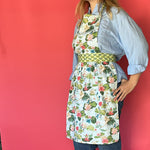 a woman wearing a green, pink and blue floral apron featuring the Meadow bluc water lilies pattern fabric from madcap cottage