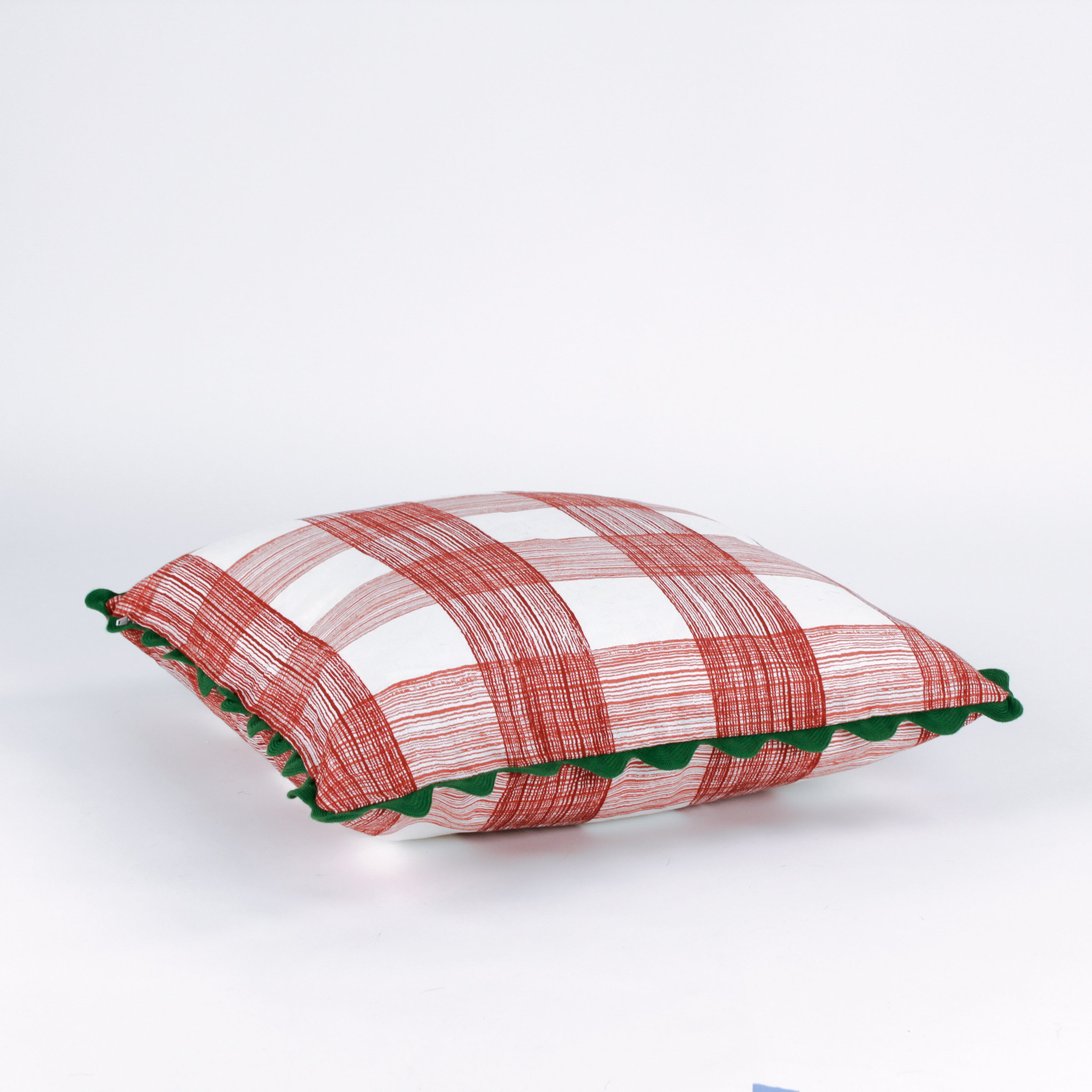 Square decorative pillow with a red gingham plaid pattern on a white background, accented with a dark green scalloped trim around the edges.