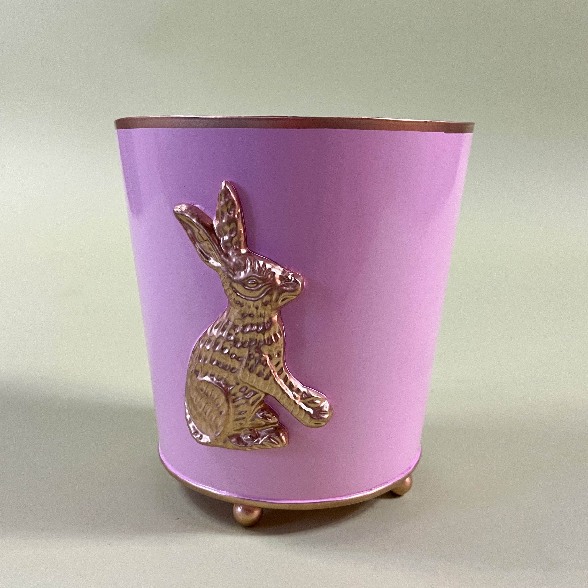a pink tole cachepot with gold bunny motif and gold detailing.