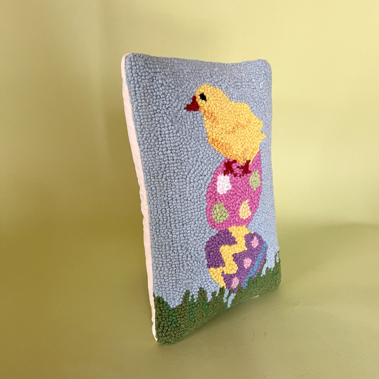 side view of A purple easter pillow with two easter eggs with a yellow chick on top