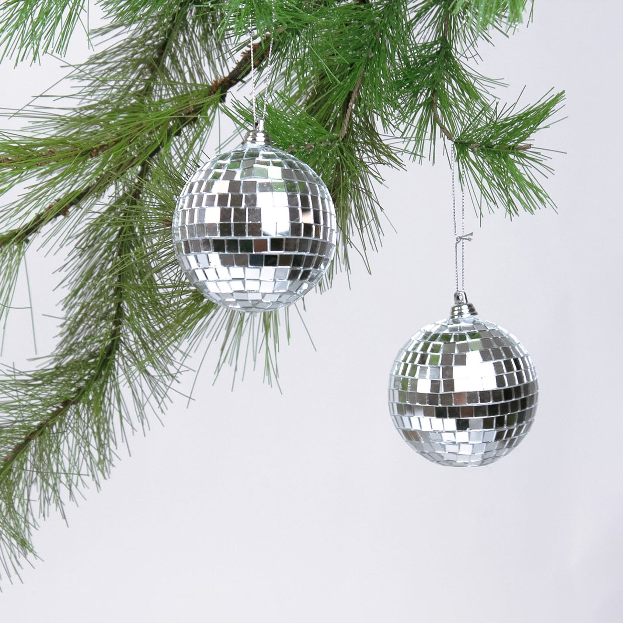2 hanging mini silver disco ball christmas ornaments on a white background