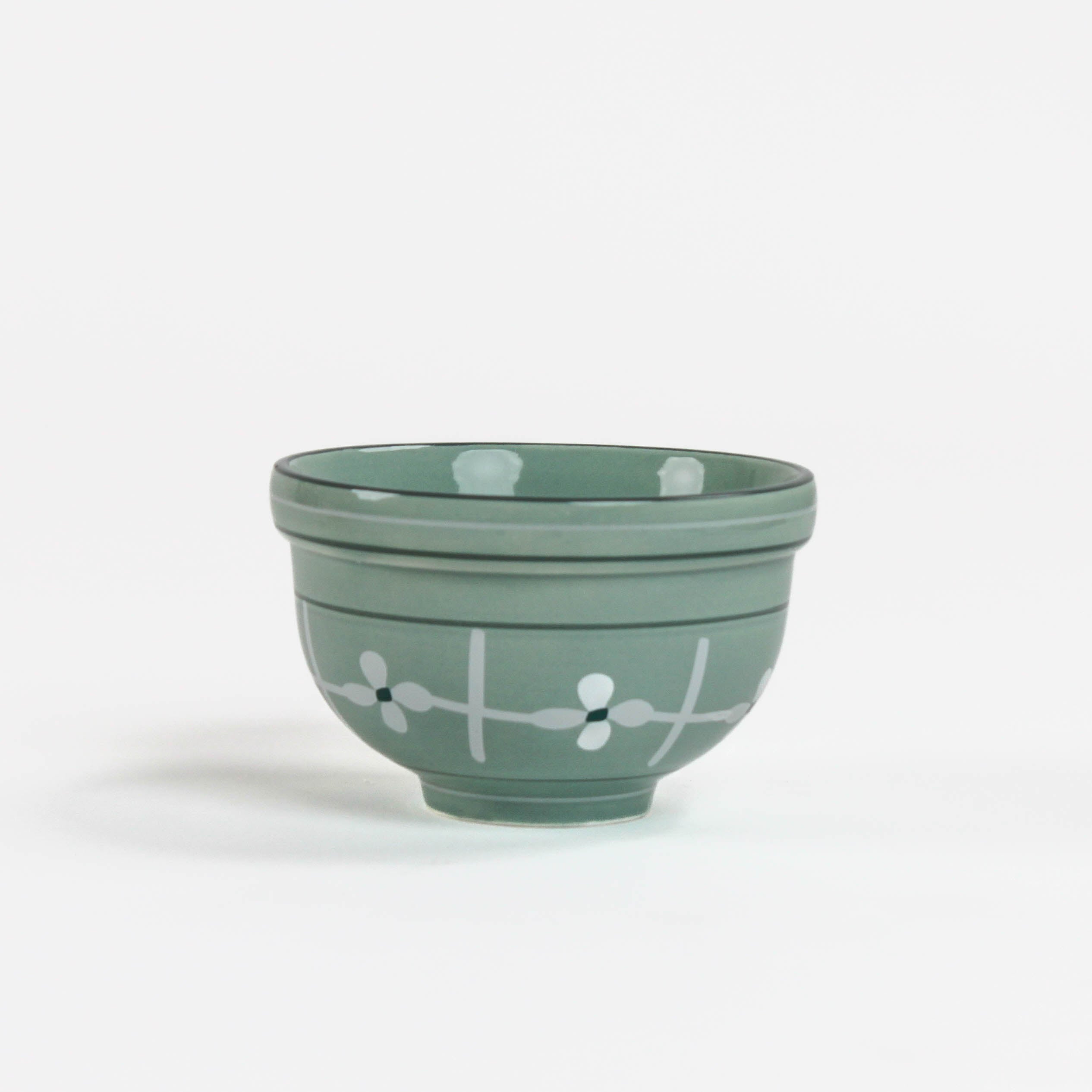 A small light green ceramic christmas bowls against a white background. 