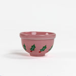 A small pink ceramic christmas bowls against a white background. 