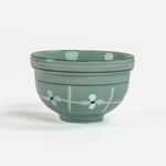 Green ceramic bowl with white floral design on a white background