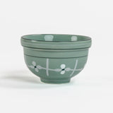 Green ceramic bowl with white floral design on a white background