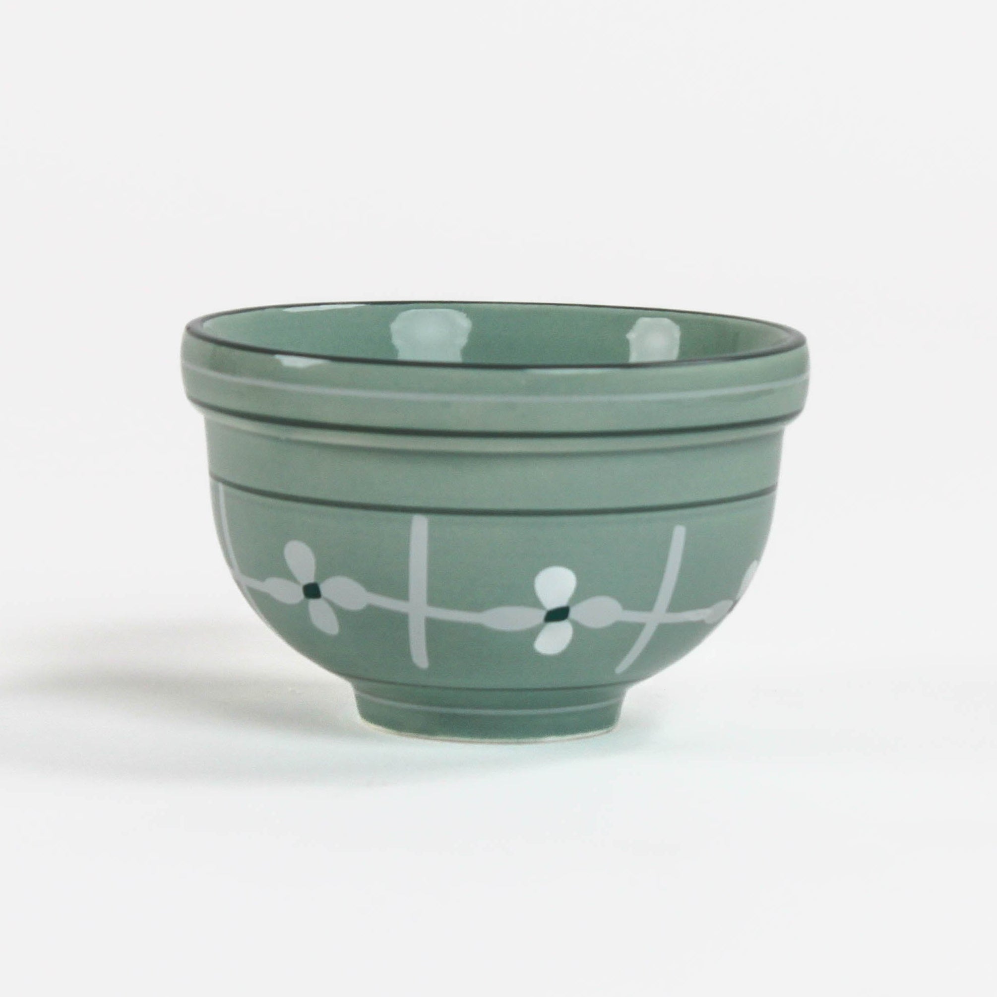 Green ceramic bowl with white floral design on a white background