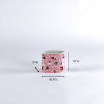 Small pink container with christmas nutcracker pattern and measurements on a white background