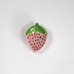 a small pink strawberry shaped bowl painted to look like a strawberry resting on a white background