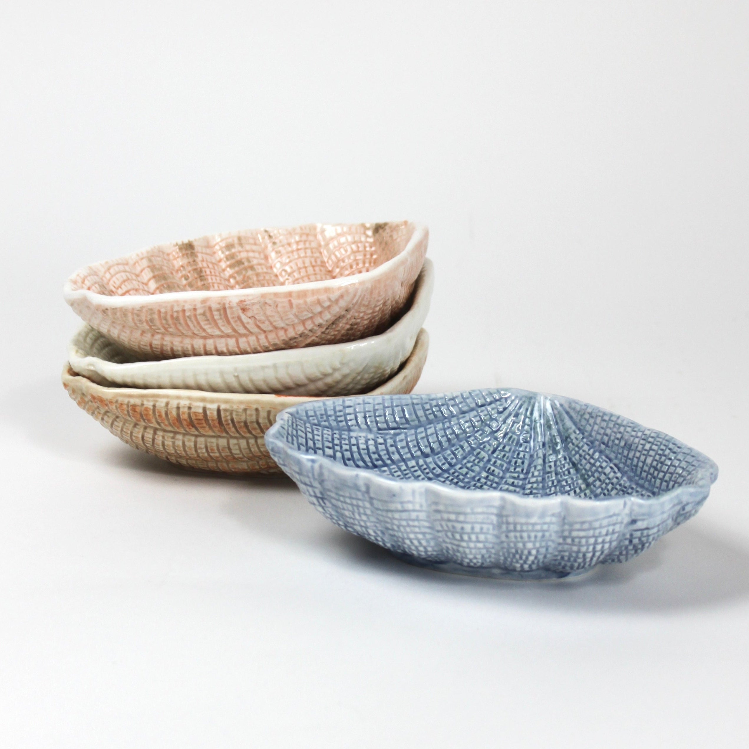 a set of blue, brown, white and pink ceramic shell bowls