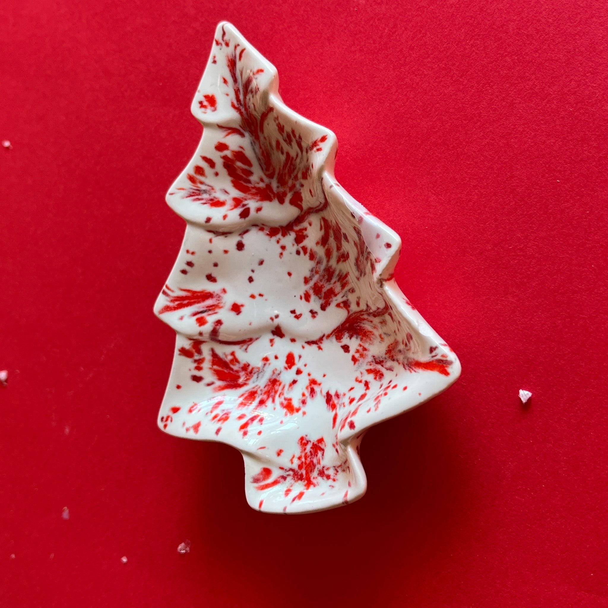 a small red and white christmas tree shape vintage plate on a red background. 