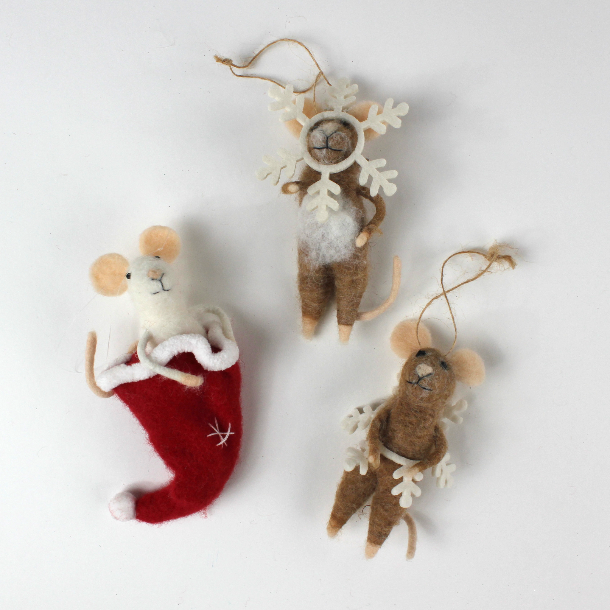 Three felt mouse ornaments, one peeking out of a red Christmas stocking and two wearing white snowflake costume frames, shown lying flat.