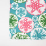 a blue christmas table runner with a pink, green and blue snowflake motif pattern against a white background. 