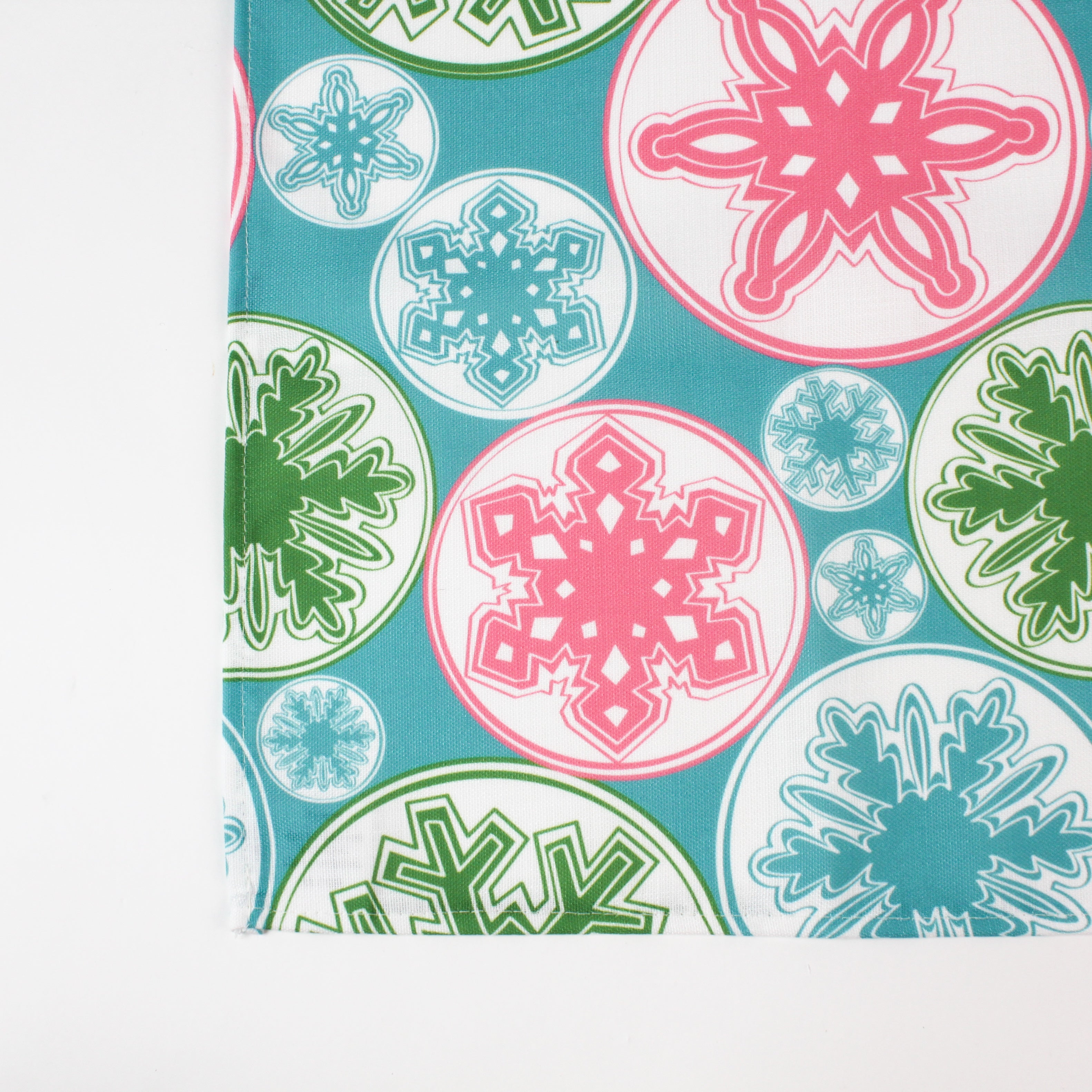 a blue christmas table runner with a pink, green and blue snowflake motif pattern against a white background. 