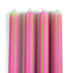 Close-up of pink taper candles with green squiggle stripe detailing for colorful spring table decor.