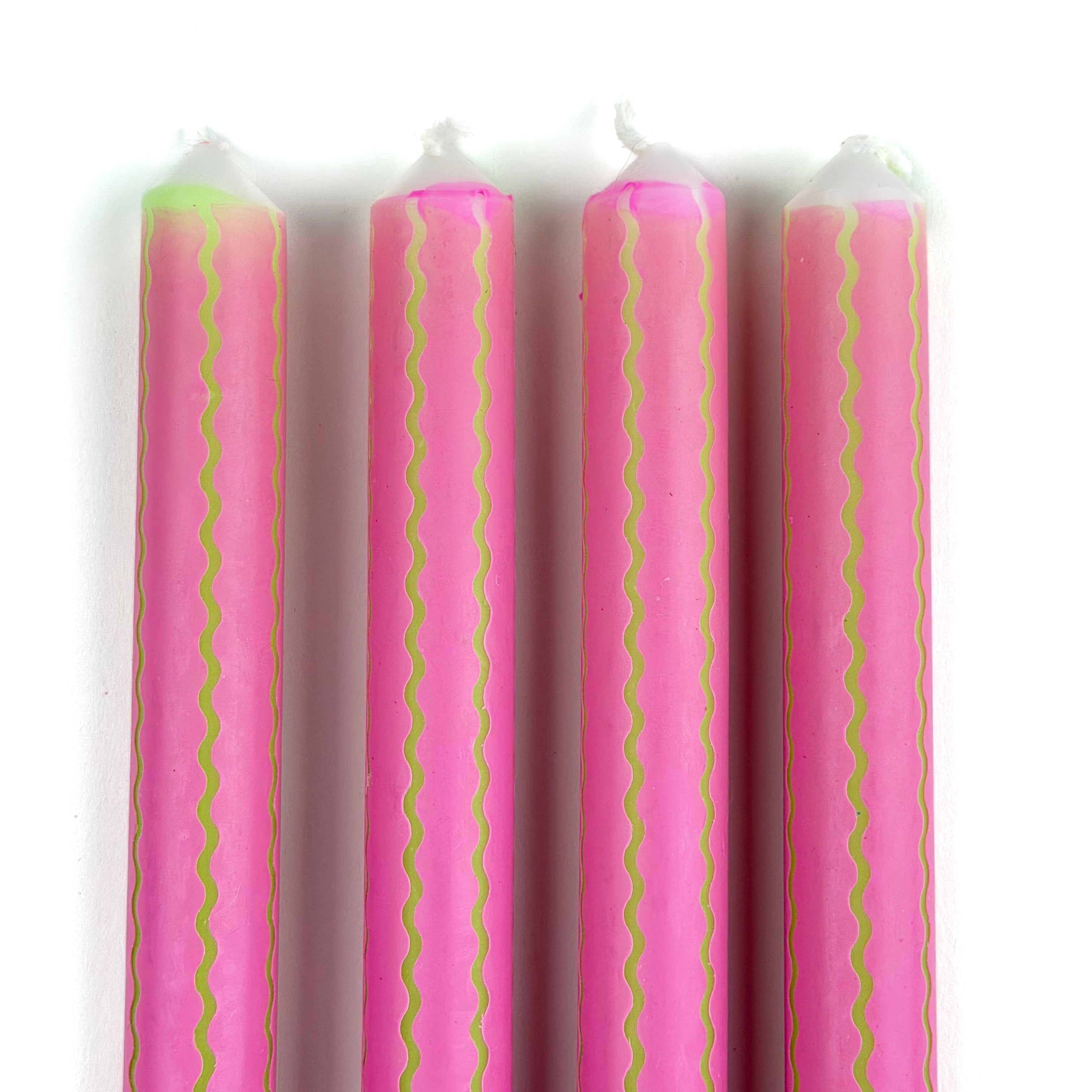 Close-up of pink taper candles with green squiggle stripe detailing for colorful spring table decor.