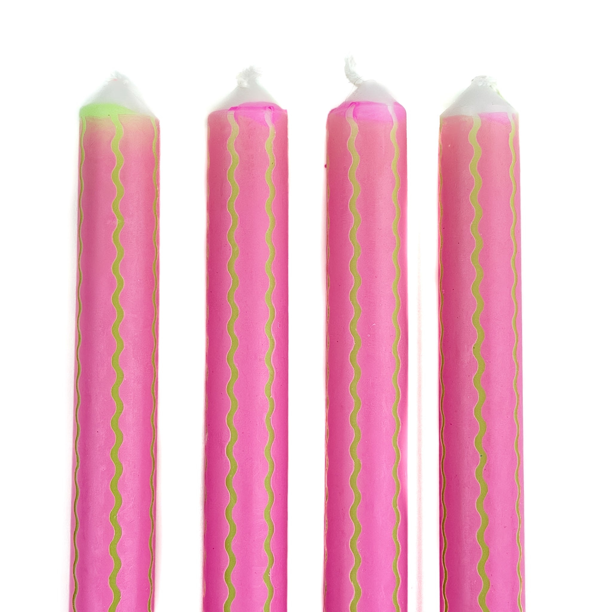 Pink taper candles with green squiggle stripe detailing arranged as a set for spring table decor.