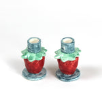 A pair of strawberry candle holders with a blue base and red strawberries forming the structure of the candle holder.