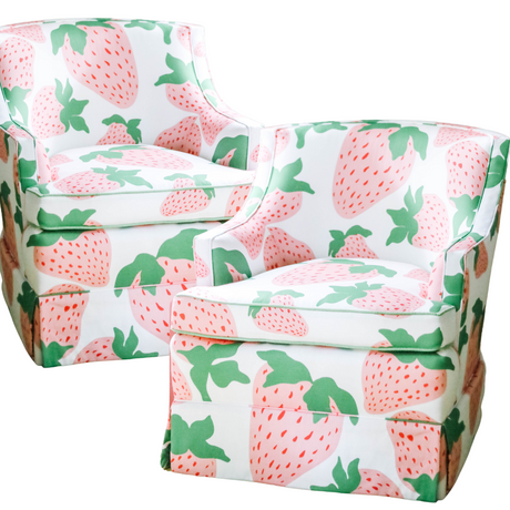 a pair of upholstered armchairs covered in strawberry fabric featuring large pink strawberries.