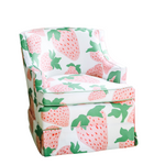 a small upholstered chair covered in strawberry fabric featuring large pink strawberries with green leaves.