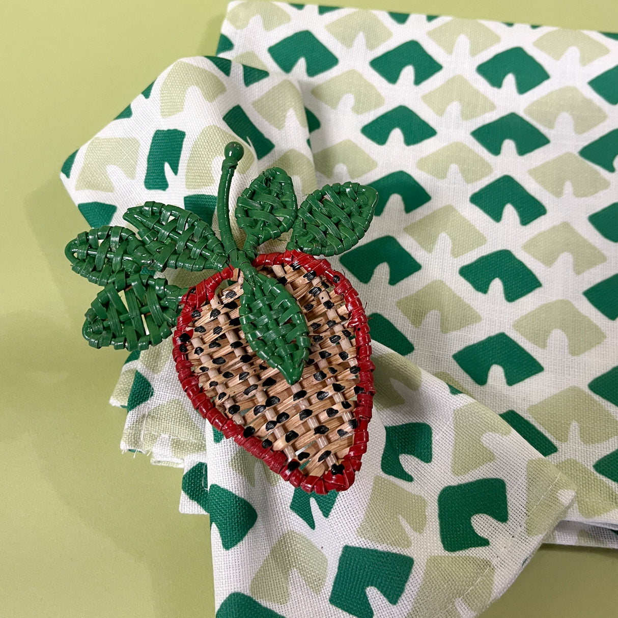 a madcap cottage old jaipur green dinner napkins that has a printed green triangle motif with strawberry napkin ring