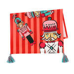 a striped christmas tea towel with four nutcracker motifs and blue and pink tasseled corners.